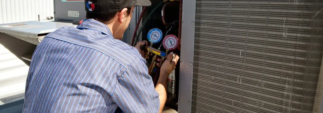 HVAC technician servicing a condenser unit in Forks