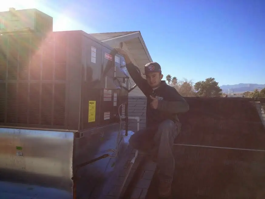 HVAC technician performing Air Duct Cleaning on a rooftop unit in Forks